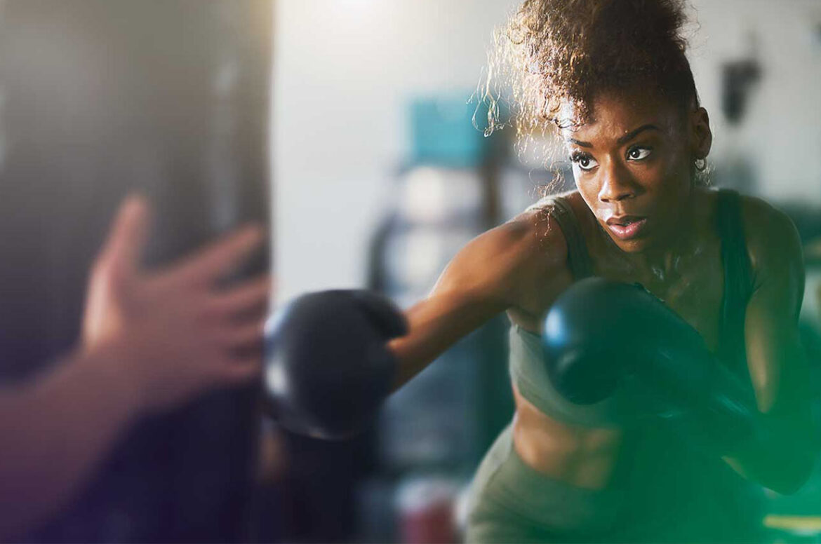A fitness center business owner wearing boxing gloves and preparing to strike.