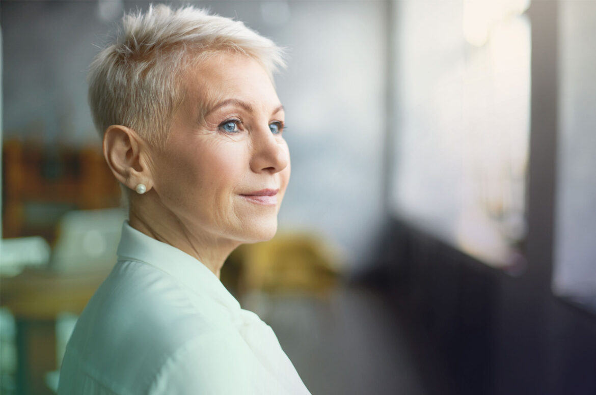 A female franchise owner is looking out of the window of her business.