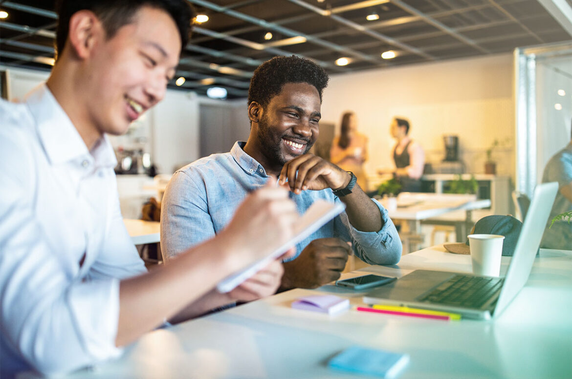 A inclusive small business owner is sitting with a client in front of a computer to work together.
