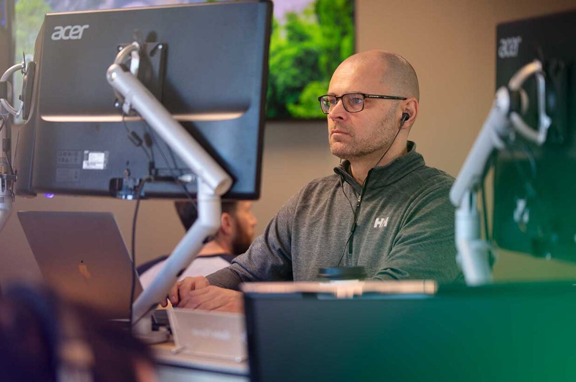 A male privacy & security expert sitting at his desk checking a security alert on his computer