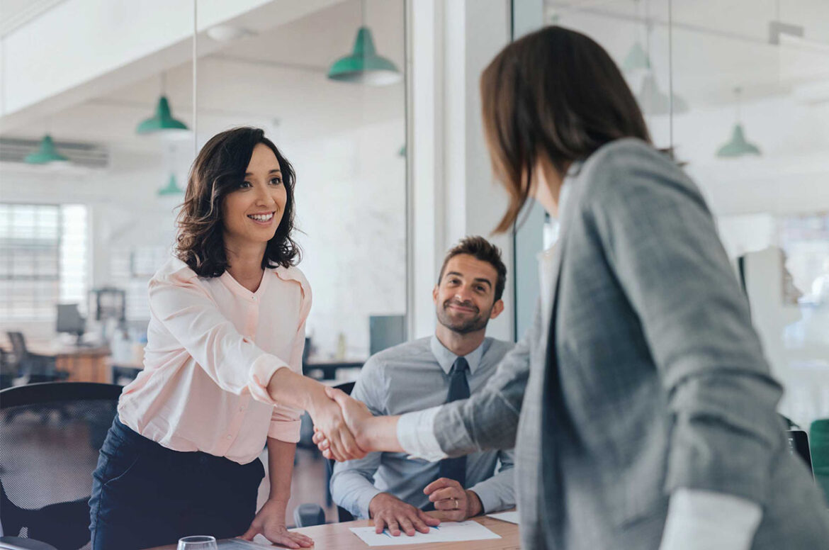 Two woman on the lender finance team shaking hands after closing a deal for a customer