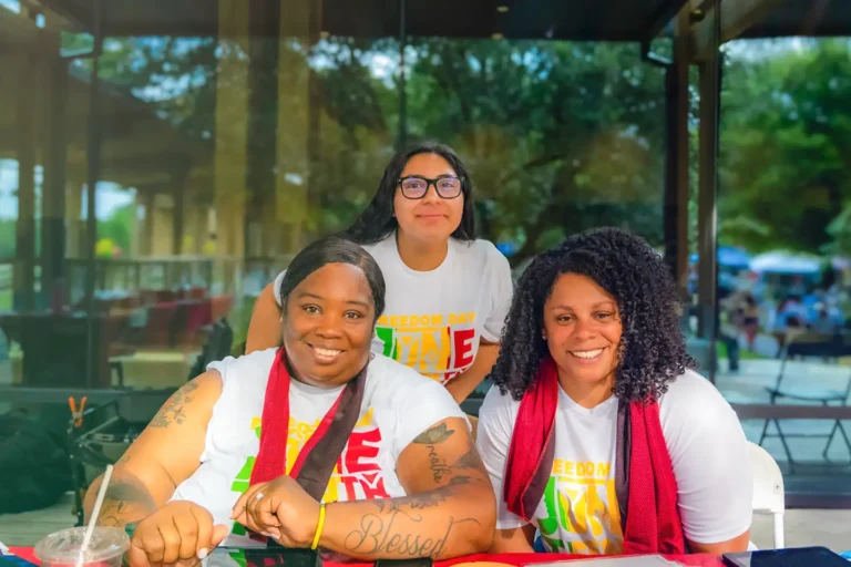 Three female members of Live Oak Bank's Minority Professionals Aligning Communities (MPAC) employee resource pose for a group photo at the 2025 Juneteenth event