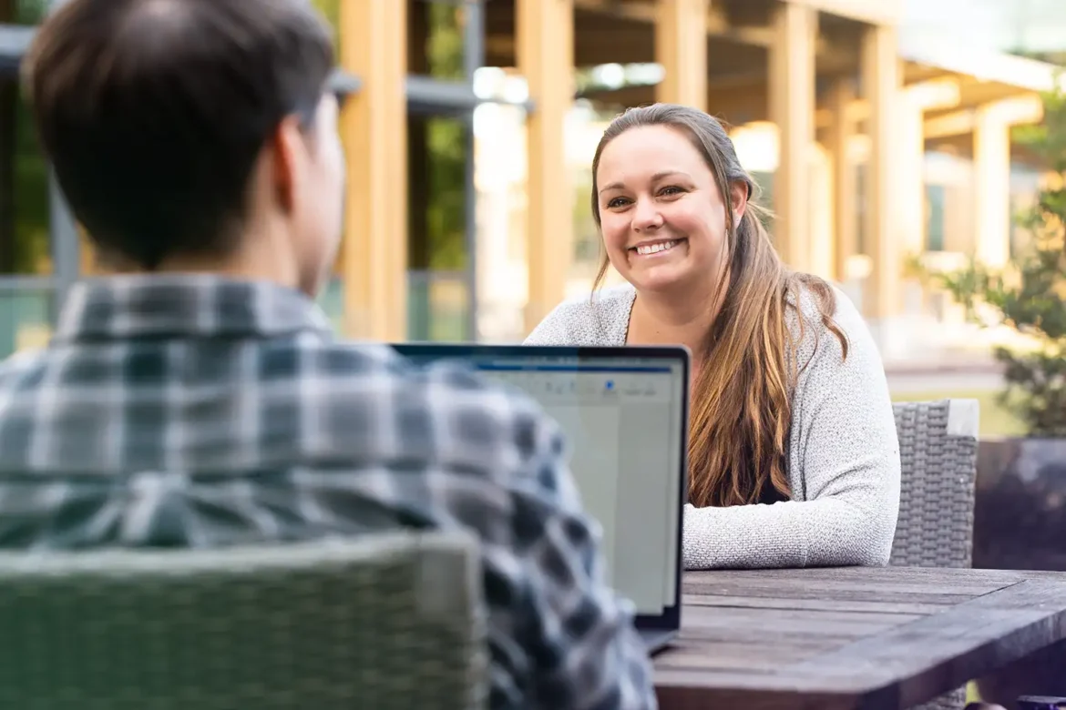 A potential job candidate speaks with a Live Oak Bank recruiter or team member on the campus grounds during the company's interview process