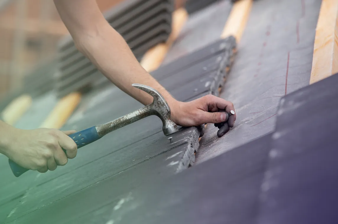 roofer nailing shingles to roof thanks to business loan solutions for commercial and residential home services contractors
